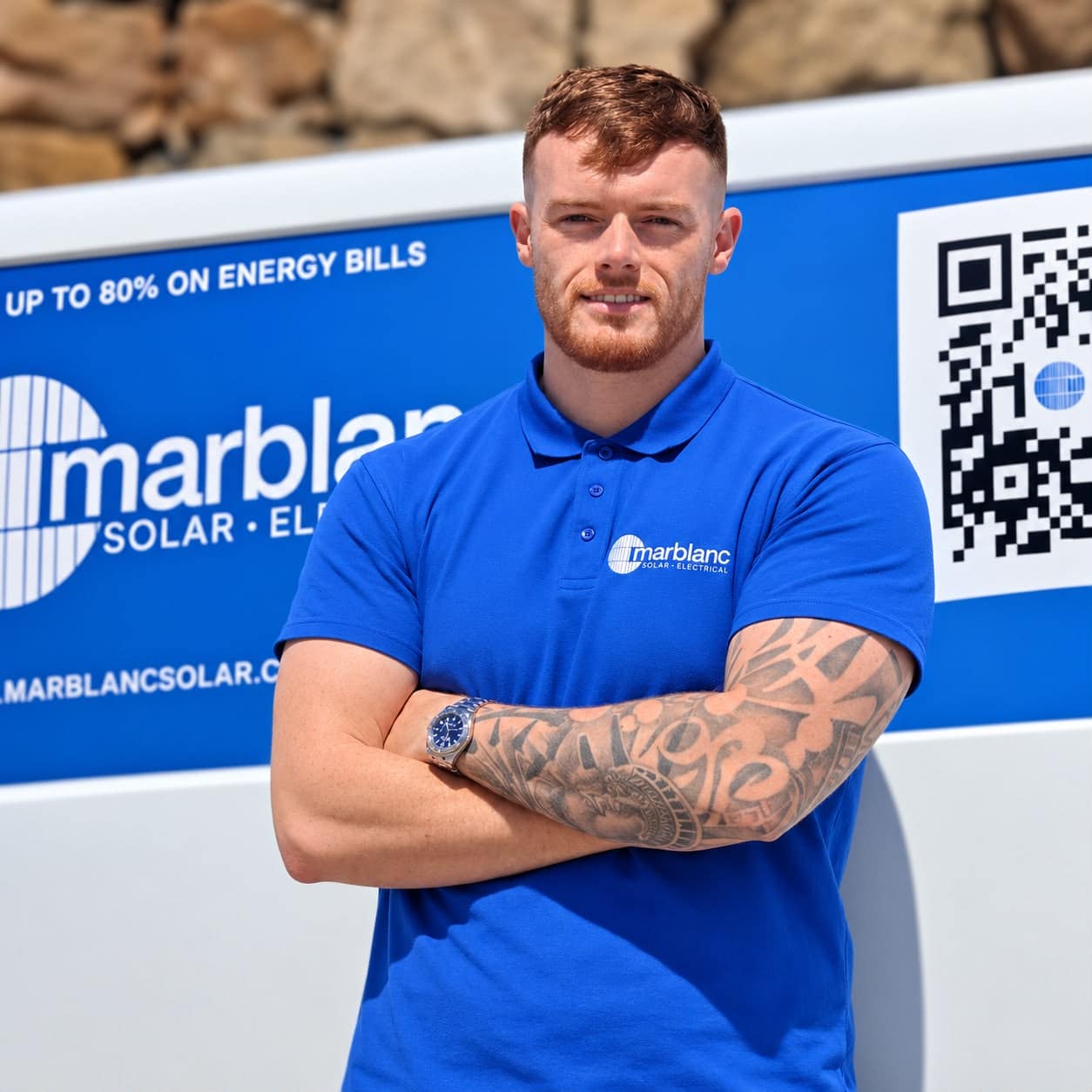 Man in a blue Marblanc Solar polo with arms crossed, standing in front of a blue company van with QR code.